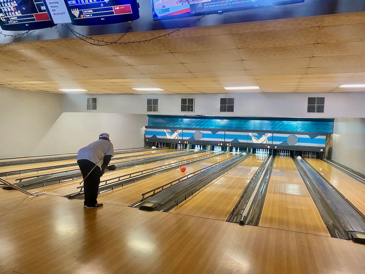 Cane tucked under his right arm, Andrew leans forward after his left-handed release. The ball speeds down the lane toward 3 standing