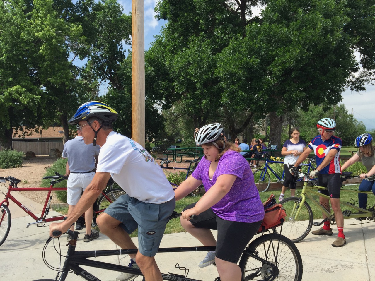 Volunteers steady tandem bicycles as students get aboard