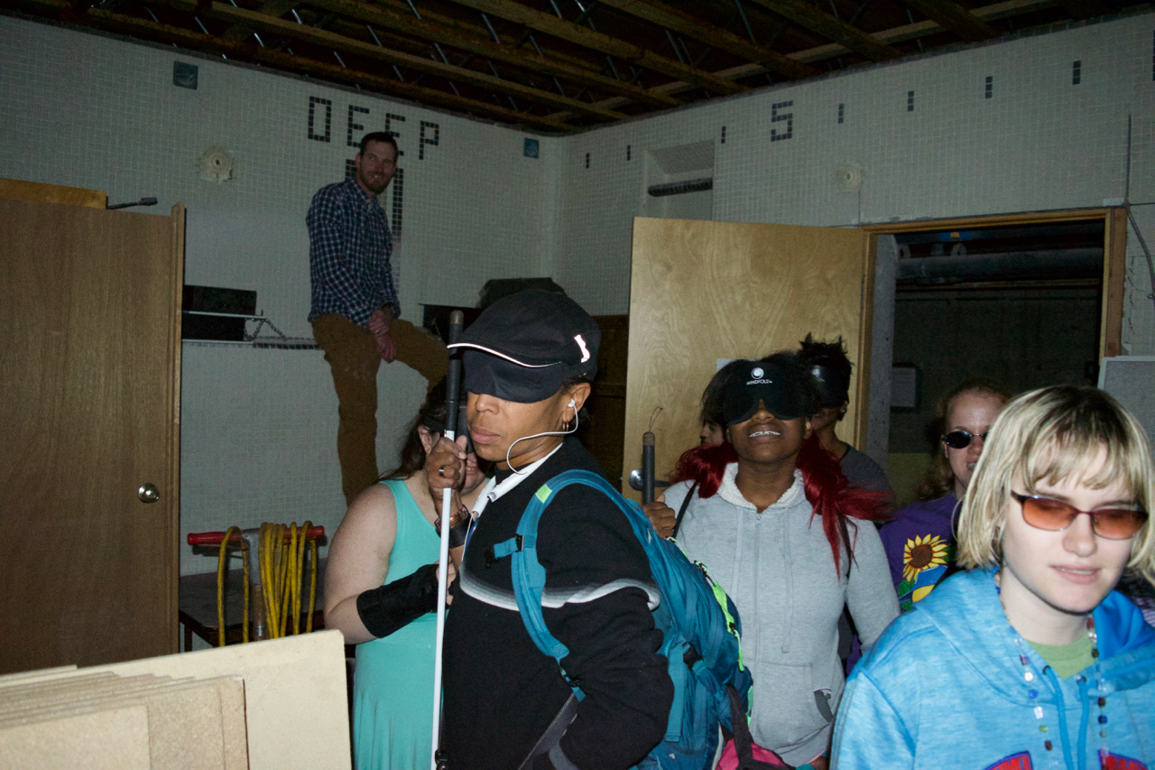 David sits on a ledge inside the pool as a group of CCB students gather in the deep end