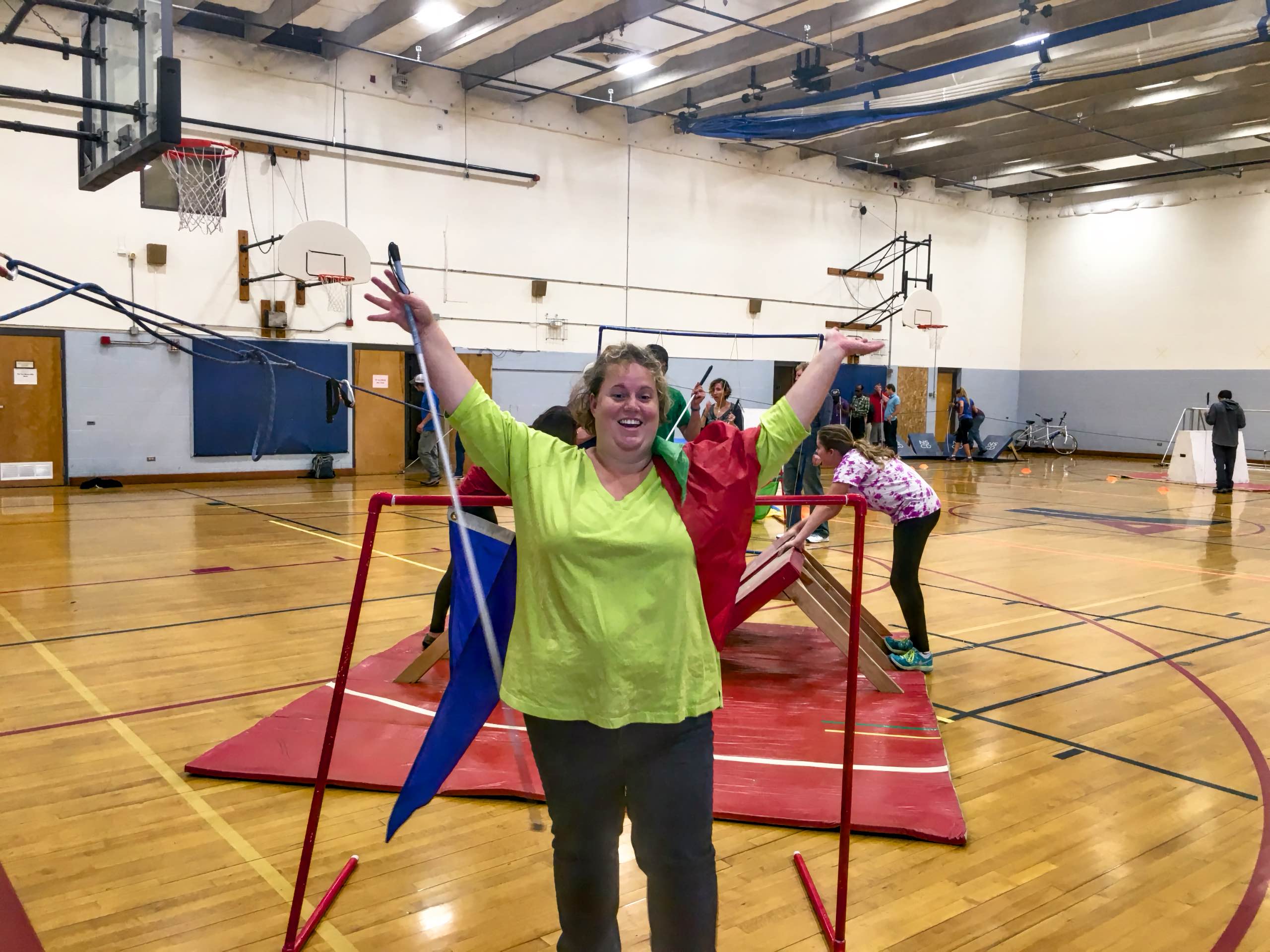 Jenny C. raises her arms in victory as she goes through the finish line of the obstacle course