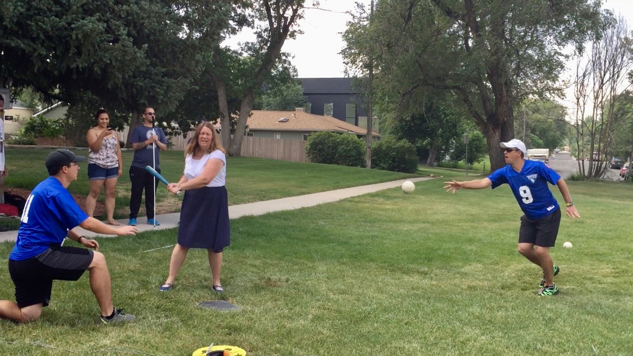 A woman swings the bat at the ball coming toward her