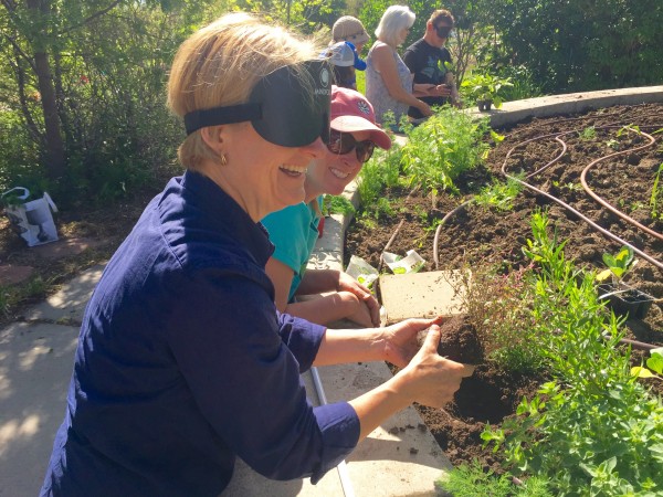 Woman wearing sleepshades reaching a small plant over its hole